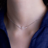 Fine jewellery, silver jewellery, hypoallergenic, tarnish-free, Close-up front view of a Silver necklace with a curve and ring crystal pendant on neck of a person wearing dark blue shirt